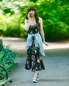 a woman walking down a road talking on a cell phone while wearing a floral dress