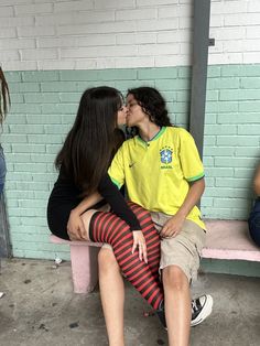 two people sitting on a bench with one kissing the other's cheek while another person is wearing striped tights