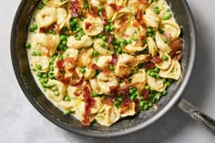 a pan filled with pasta, peas and bacon