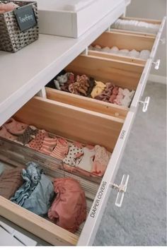 an open drawer in a closet filled with clothes