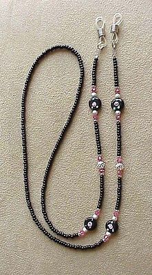 a black beaded necklace with skulls and pink beads