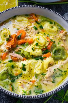 a white bowl filled with chicken noodle soup and garnished with parsley