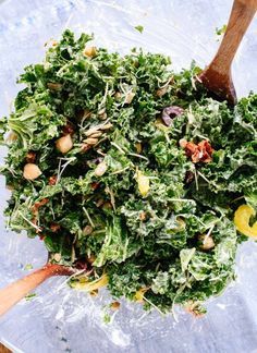 a pile of green vegetables sitting on top of a blue table cloth next to a wooden spoon