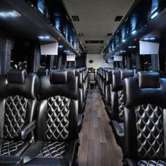 the interior of an empty bus with black leather seats and wood flooring on both sides