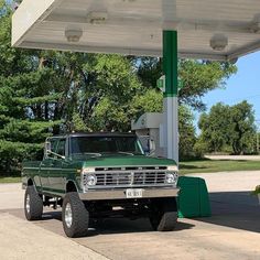 a green truck parked at a gas station