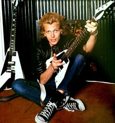 a man sitting on the floor with an electric guitar in his hand and looking at the camera