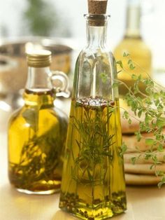 two bottles filled with olive oil and herbs