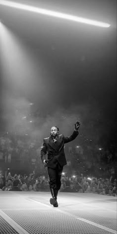 a black and white photo of a man in a suit running on a runway