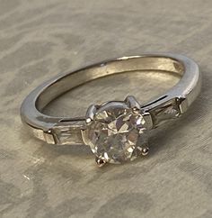 an engagement ring with three baguets on the side and a diamond in the middle