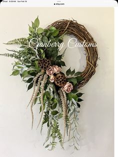 a wreath with flowers and greenery hanging on the wall