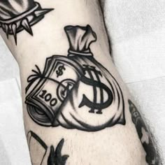 a man's arm with tattoos on it, including money bags and other symbols