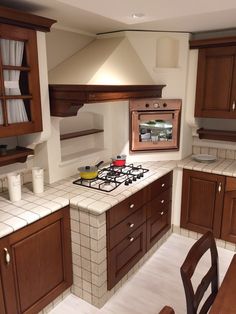 a kitchen with wooden cabinets and white tiled counter tops, along with a stove top oven