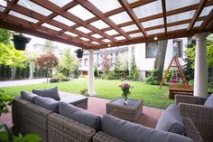 an outdoor living area with couches, chairs and a wooden pergoline roof