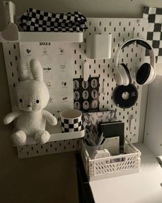 a white teddy bear sitting on top of a desk next to headphones