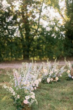 wedding flowers lined up on the grass in front of trees