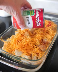 someone is adding cheese to a casserole dish