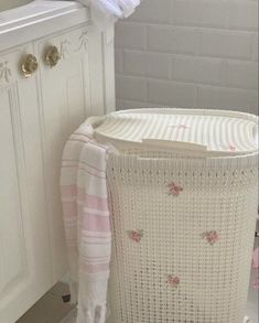 a white laundry basket sitting next to a toilet