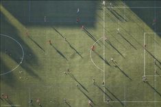 an overhead view of people playing soccer on a green field with shadows from the sun