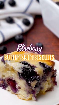 a slice of blueberry butter swim biscuits on a plate with the rest of the cake in the background