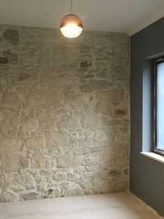 an empty room with a stone wall and window