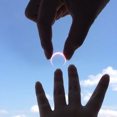 two hands reaching out towards each other with the sky in the background