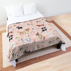 a bed covered in a pink blanket with dogs and cats all over it on top of a wooden floor