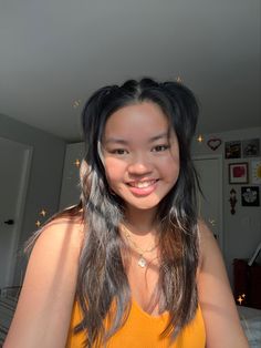 a woman with long hair smiling at the camera while wearing a yellow shirt and gold necklace