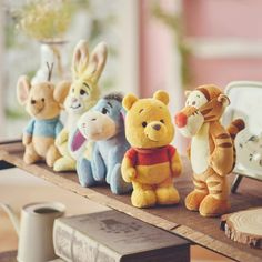 several winnie the pooh stuffed animals are lined up on a table next to an alarm clock