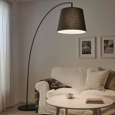 a living room with a white couch, table and lamp on the wall next to it