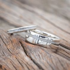 two silver rings sitting on top of a wooden table