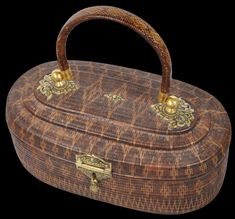 an old wooden box with gold handles on a black background and the lid is covered in wicker