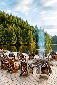 there are many chairs on the dock with an open fire pit in front of them