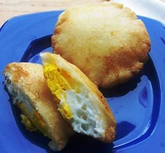 two fried eggs are sitting on a blue plate next to an egg muffin that has been cut in half