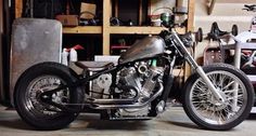 a motorcycle parked in a garage next to a shelf filled with tools and other items