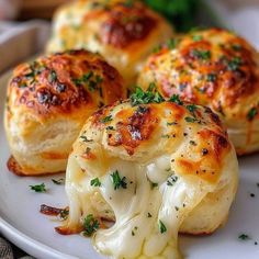 three pieces of bread with cheese and herbs on it sitting on a white plate next to broccoli