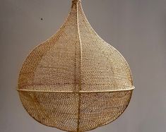 a hanging basket made out of woven material on a wooden stand with an iron hook