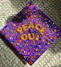 a purple graduation cap with the words peace out on it and confetti sprinkles