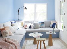 a living room with blue walls and white furniture, including a large sectional couch in the center