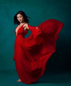 a woman in a long red dress is posing for the camera with her hands on her hips