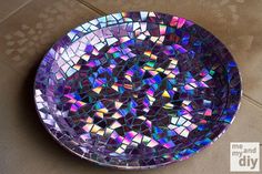 a plate that has been made out of glass mosaics and is sitting on the floor