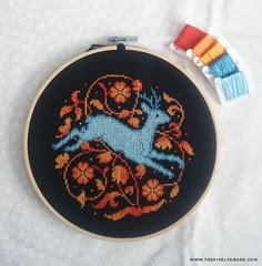 a cross stitch pattern with an animal on it next to some spools of thread