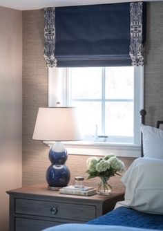 a bed room with a neatly made bed next to a night stand and window sill