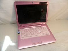 a pink laptop computer sitting on top of a bed