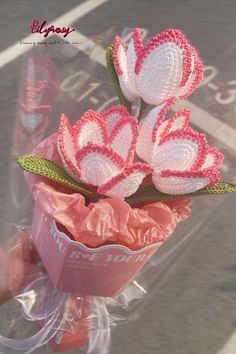 crocheted flowers are in a plastic bag on the side of the road,