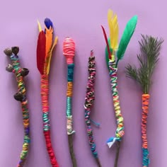 four different types of feathers and beads on a purple surface with pine branches in the foreground