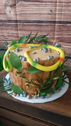 a cake that is sitting on top of a wooden table with green leaves and beads