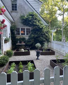 an outdoor garden area with various plants and flowers in the center, surrounded by a white picket fence