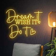 a neon sign that says dream it, do it on the wall next to a chair