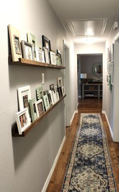 a long hallway with pictures on the wall and framed photos on the shelves above it