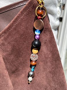 a woman's handbag with an assortment of beads hanging from the front pocket